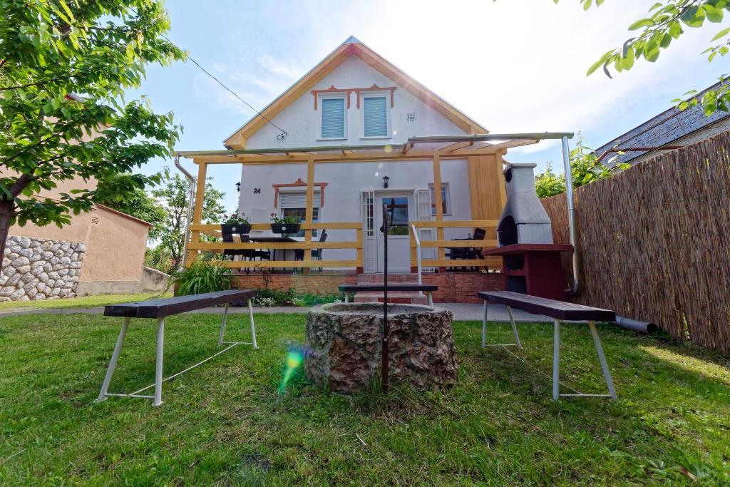 a house with two picnic tables in the yard at Zsoryka Vendégház in Mezőkövesd