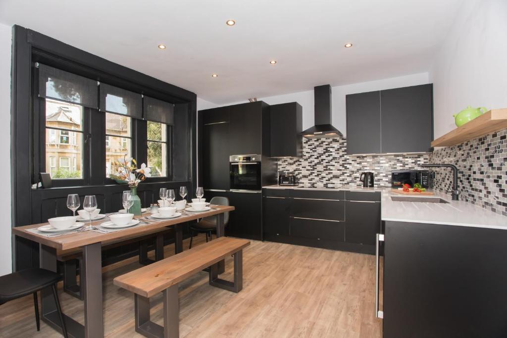 a kitchen with black cabinets and a wooden table at Locksbrook Lodge - Hot Tub - Spacious Outdoor Space in Bath