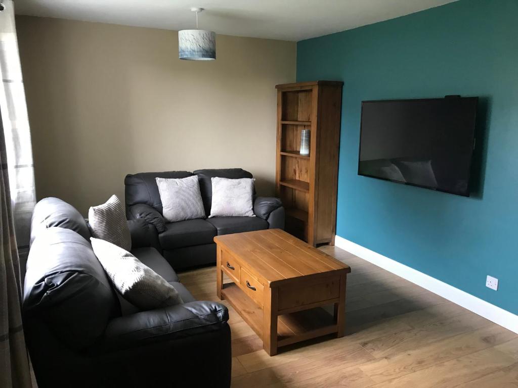 uma sala de estar com um sofá preto e uma televisão em Heb Holiday, Self Catering Accommodation, Isle of Benbecula em Gramisdale