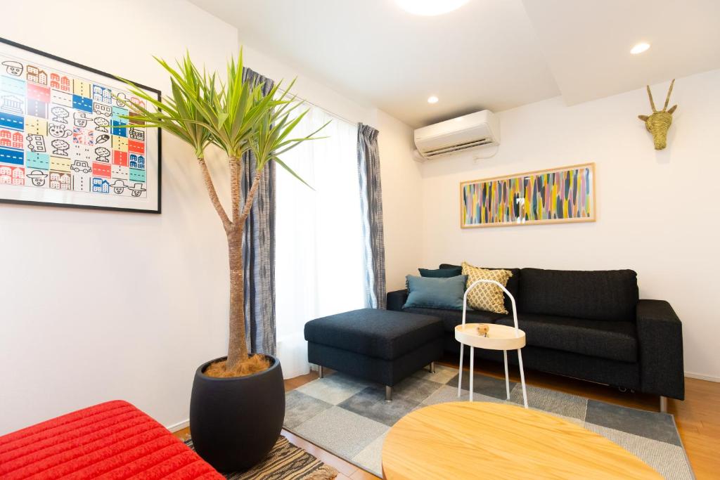 uma sala de estar com um sofá preto e uma palmeira em Sangen-jaya House-O em Tóquio