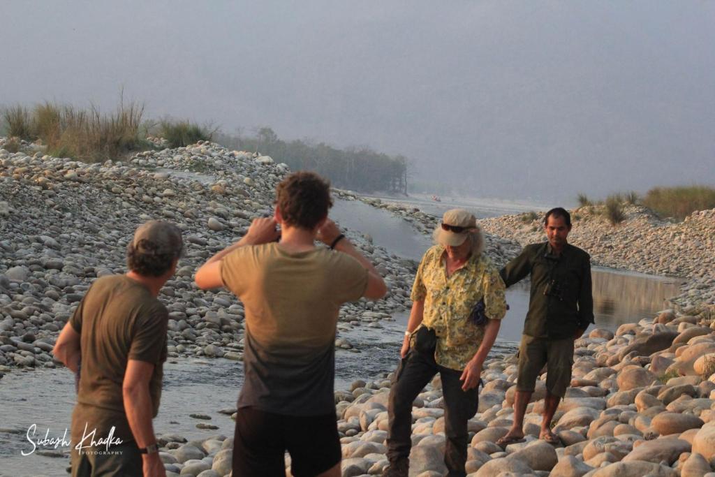 a group of men standing on the rocks near a river at Bardia Jungle Cottage in Bardiyā