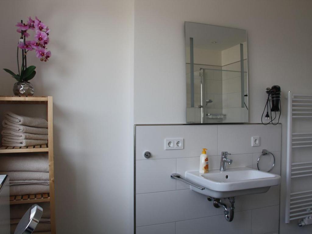 La salle de bains blanche est pourvue d'un lavabo et d'un miroir. dans l'établissement Zum großen Zernsee am Hafen, à Kolonie Roeske
