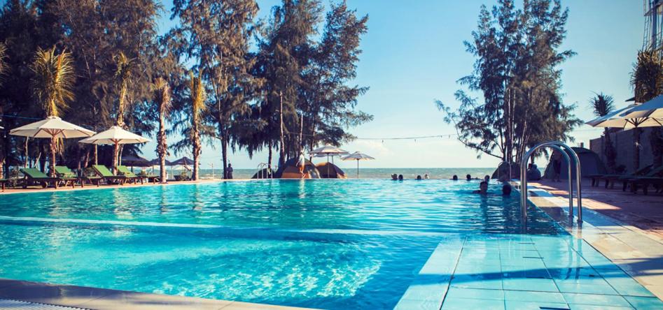 una piscina accanto a una spiaggia con ombrelloni di Cam Bình Resort a La Gi