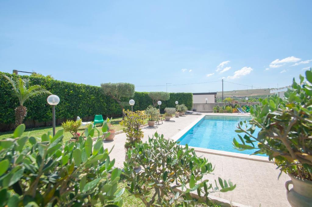 een zwembad met bomen en planten eromheen bij B&b Vittoria House in Carlentini