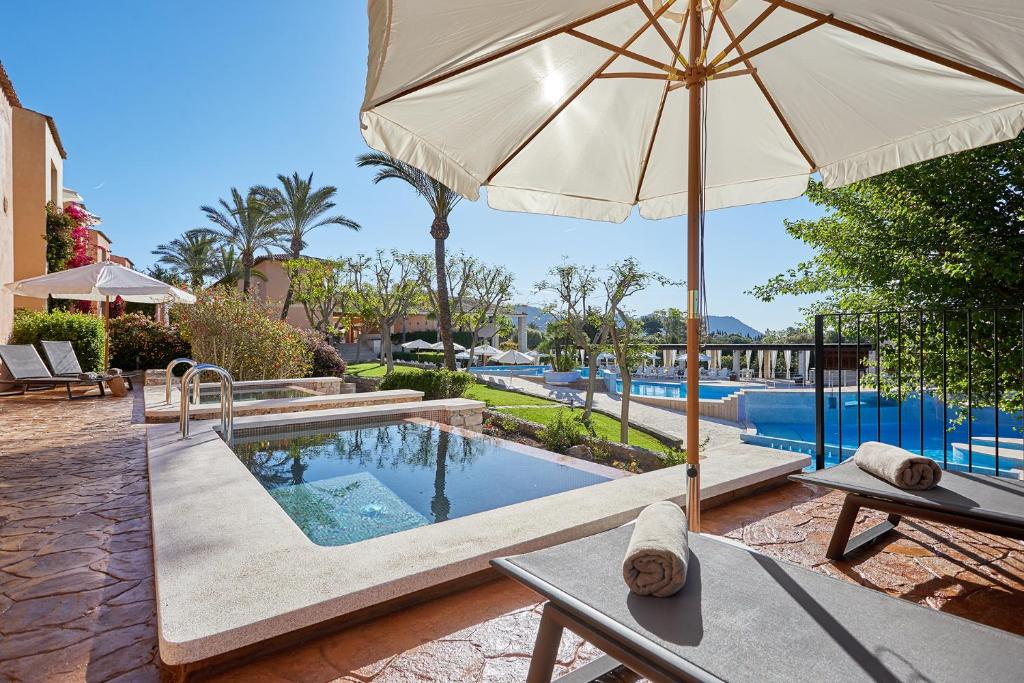 松塞爾韋拉的住宿－Pula Suites Boutique Resort，一个带遮阳伞和桌子的游泳池以及游泳池