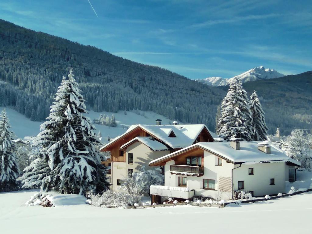 una casa en la nieve con árboles nevados en Appartments Helvetia, en Villabassa