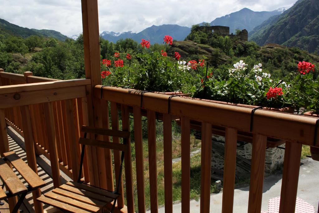 una terrazza in legno con panchina e fiori su una montagna di Maison Chenal a Montjovet