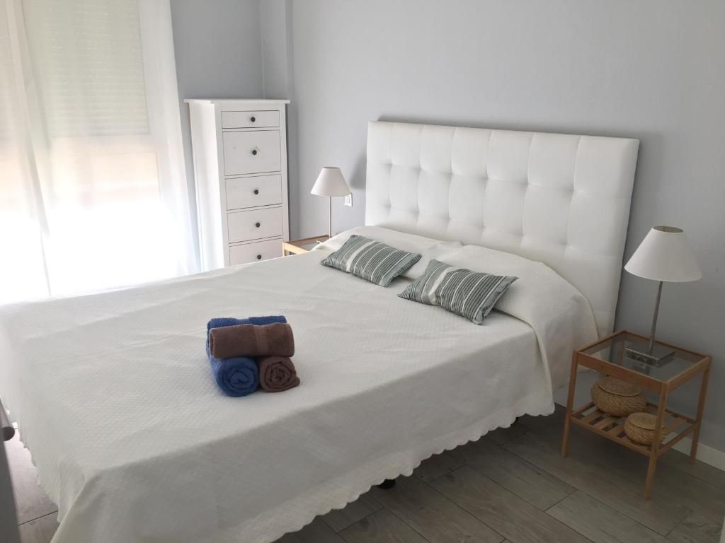 a bedroom with a white bed with a large white headboard at Apartamento Ideal in El Médano