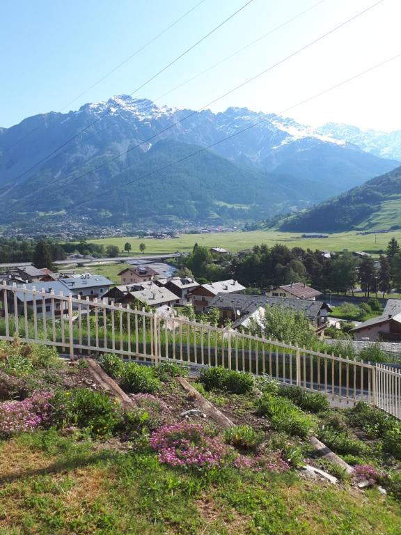 un villaggio con una recinzione bianca e montagne sullo sfondo di Casa ai Ross a Valdisotto