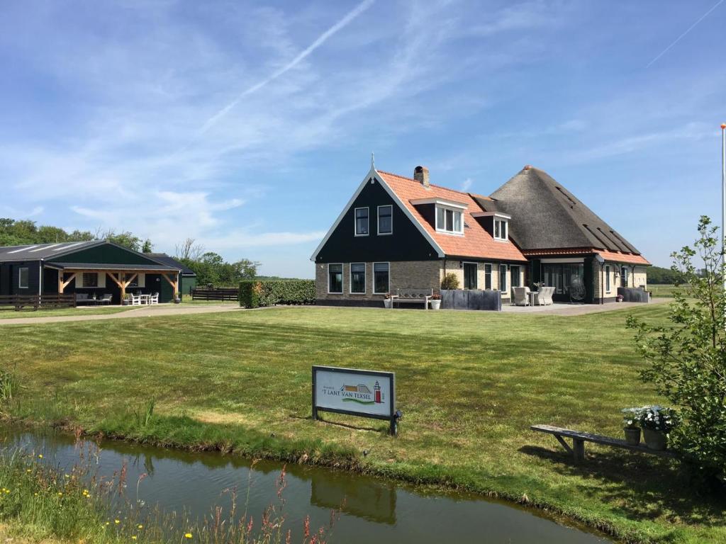 ein Haus mit einem Strohdach und einem Teich in der Unterkunft 't lant van Texsel in De Koog