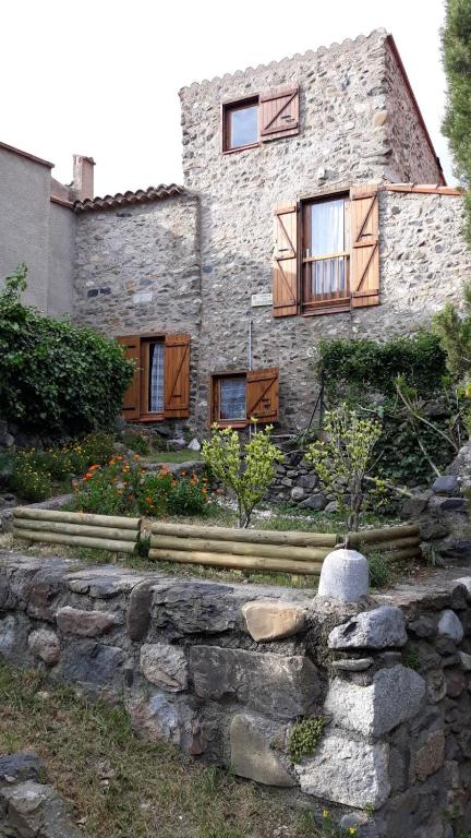une maison en pierre avec des fenêtres et un mur en pierre dans l'établissement Le gîte du Fort, à Caudiès-de-Fenouillèdes