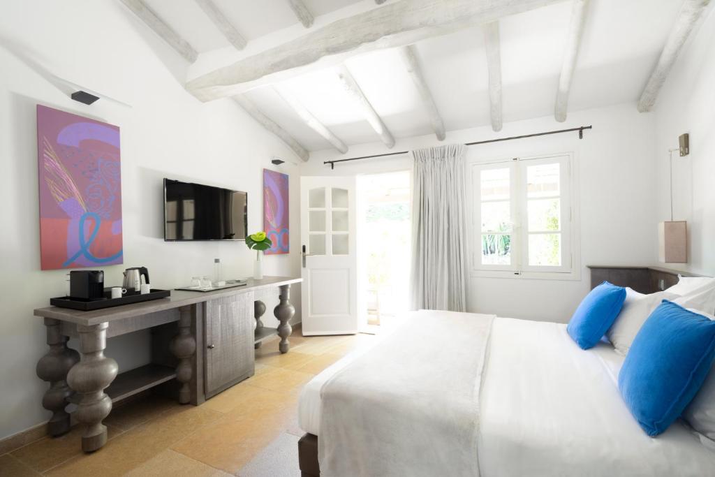 a white bedroom with a bed and a desk at Le Pre de la Mer in Saint-Tropez