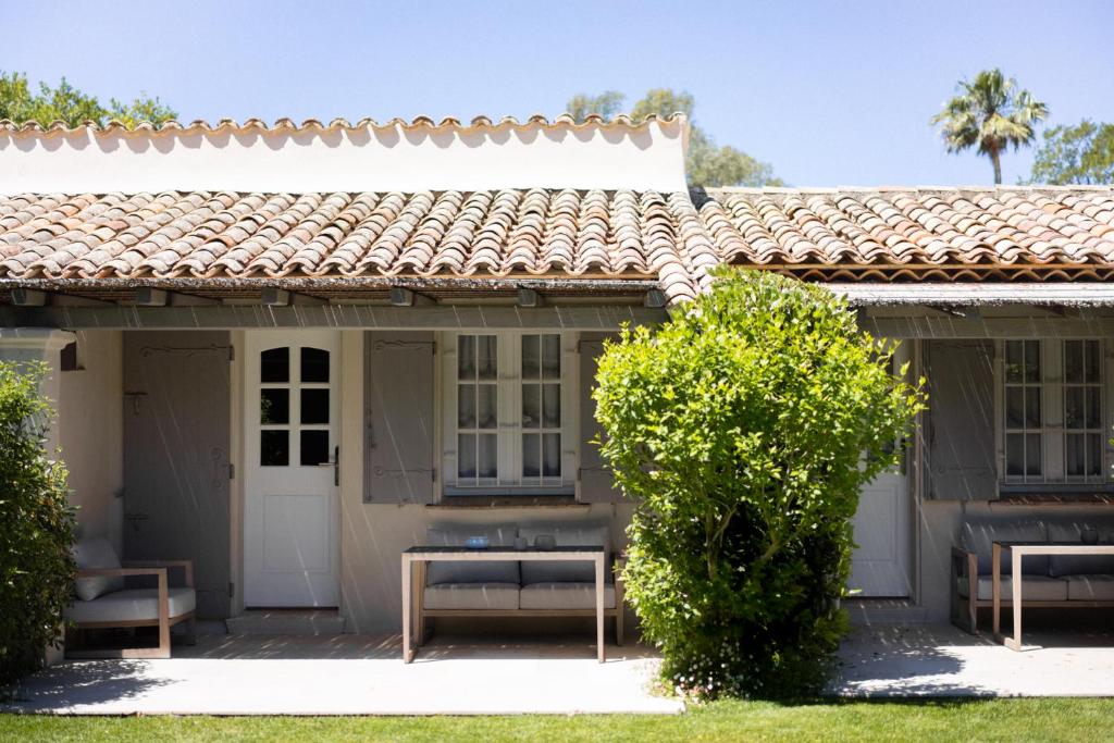 a house with two benches in the front yard at Le Pre de la Mer in Saint-Tropez