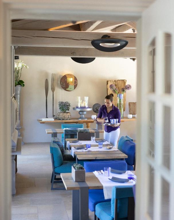 a woman standing in a dining room with tables at Le Pre de la Mer in Saint-Tropez