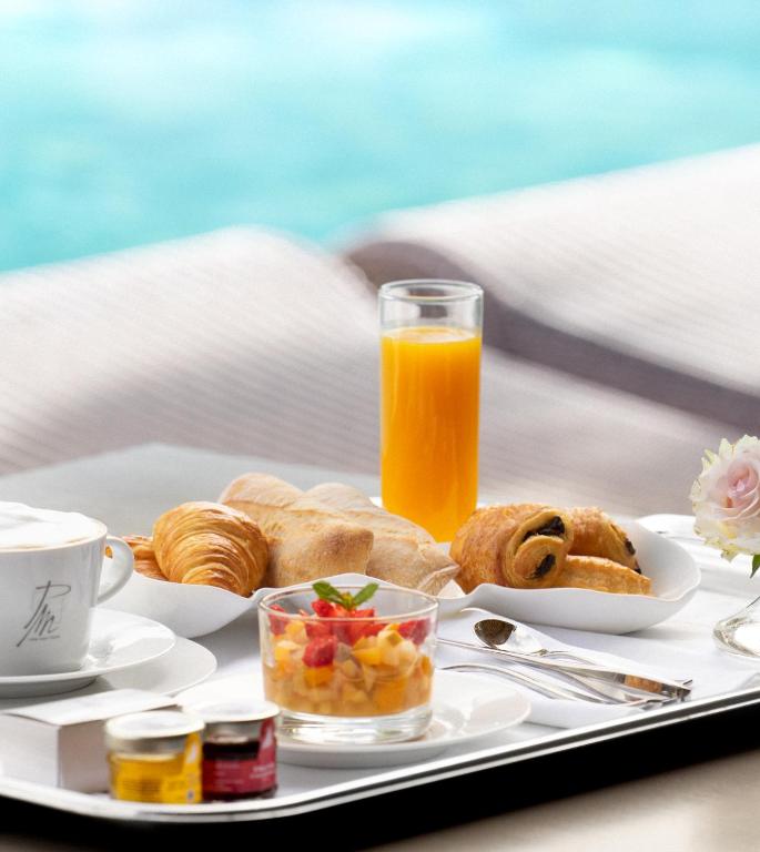 a tray with breakfast foods and a glass of orange juice at Le Pre de la Mer in Saint-Tropez