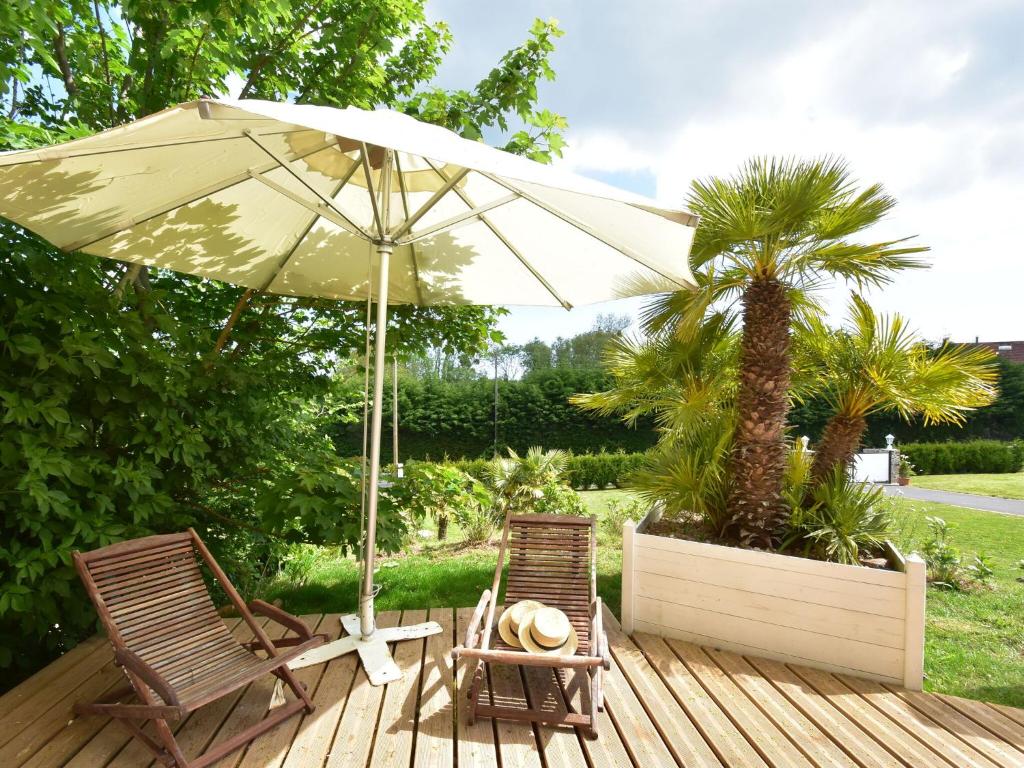 twee stoelen en een parasol op een houten terras bij Superb holiday home near the beach in Quinéville