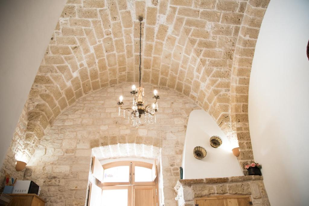 żyrandol wisi na suficie kamiennej ściany w obiekcie Piazza Duomo - Medieval Puglia's House w mieście Giovinazzo