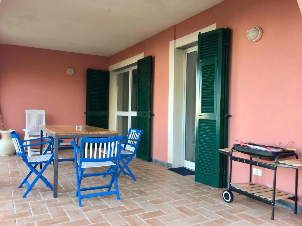 a patio with blue chairs and a table and green doors at Rossola House in Bonassola
