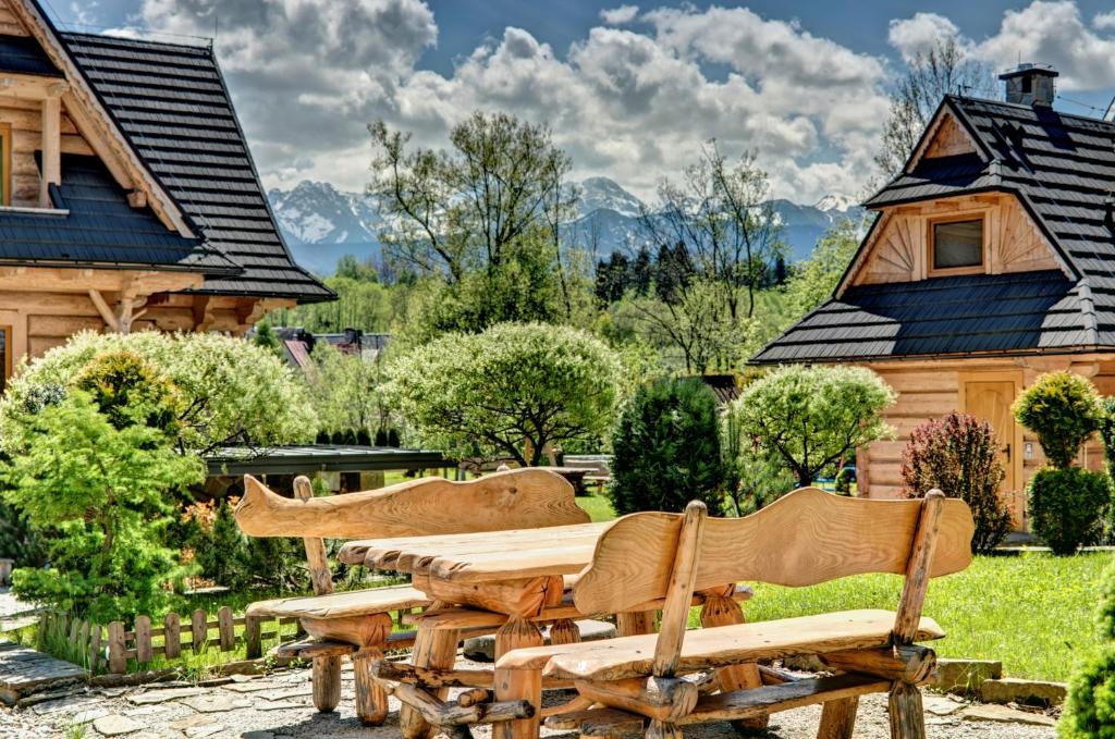 uma mesa de madeira e cadeiras em frente a uma casa em Osada Harenda em Zakopane