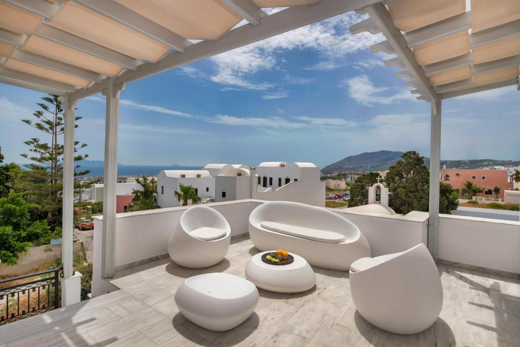 a balcony with white chairs and a view of a city at Villa Soula in Fira