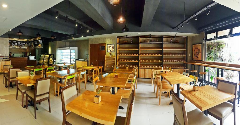 a restaurant with wooden tables and chairs in a room at Golden Valley Hotel in Cebu City