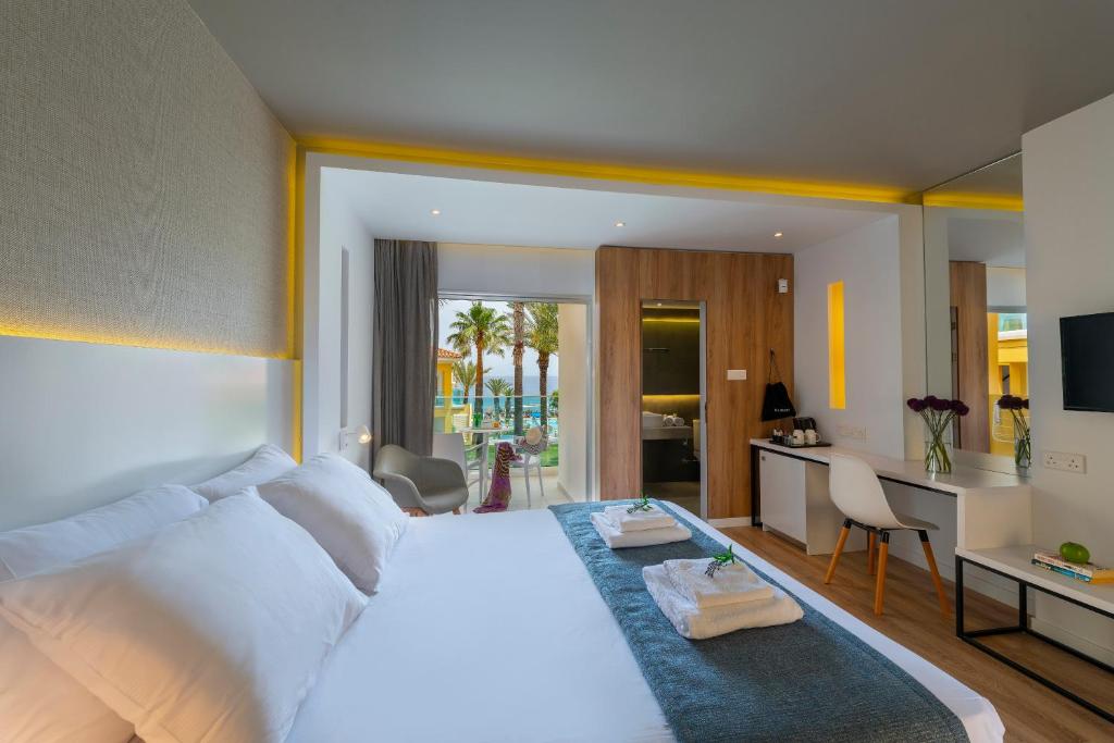 a bedroom with a large white bed and a kitchen at Malama Beach Holiday Village in Protaras