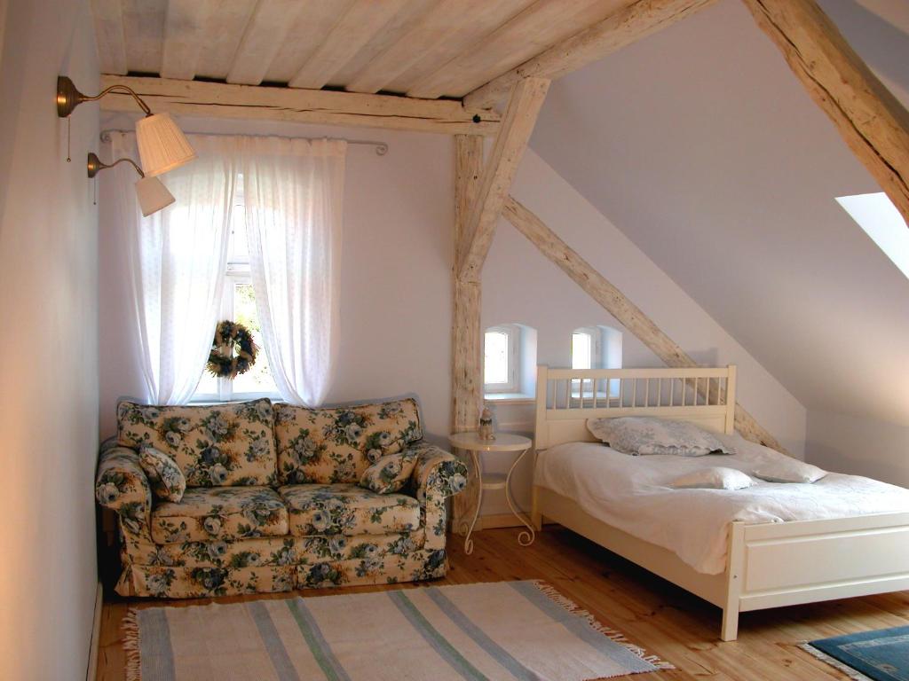 a bedroom with a bed and a couch and a window at Dom Gościnny Ogłuszka in Pilec