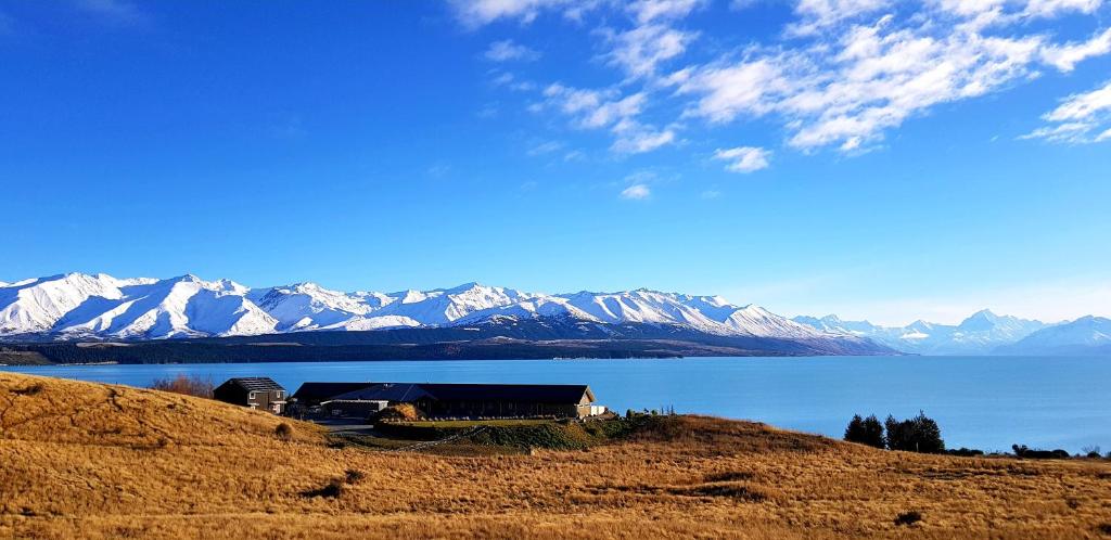 a house on a hill next to a body of water at Lakestone Lodge in Lake Pukaki