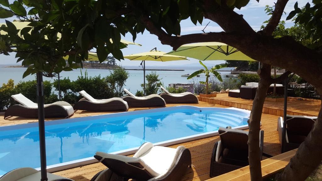 a swimming pool with chairs and an umbrella at Banjol 441 Apartman mare in Rab
