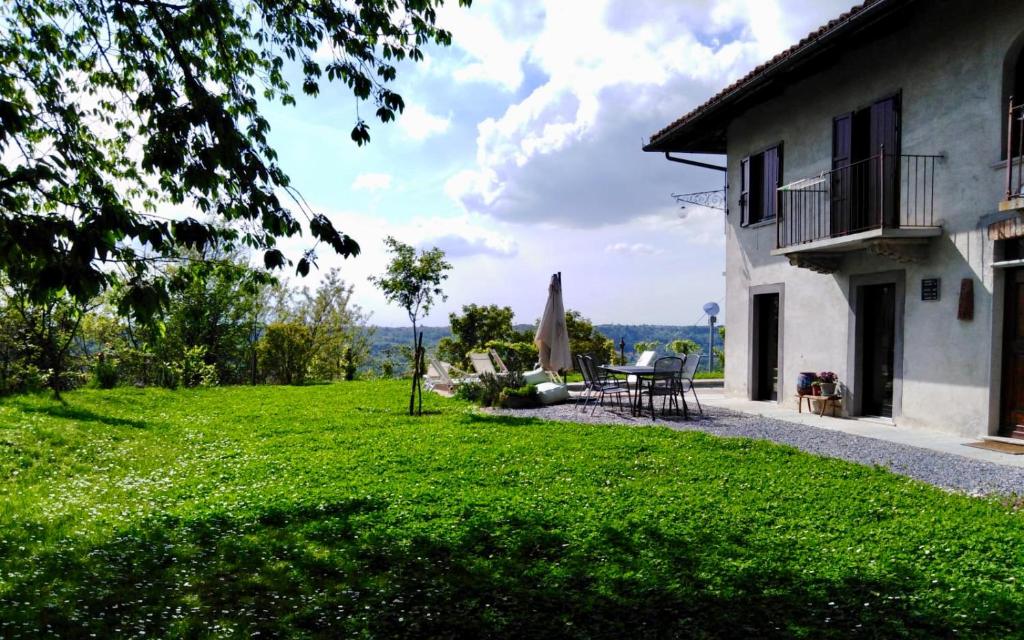 ein Haus mit einem grünen Garten mit einem Tisch und einer Terrasse in der Unterkunft Cascina Linét in Novello