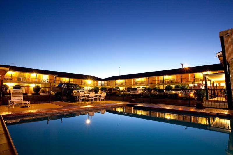 a swimming pool in front of a building at night at Golden West Motor Inn in Dubbo