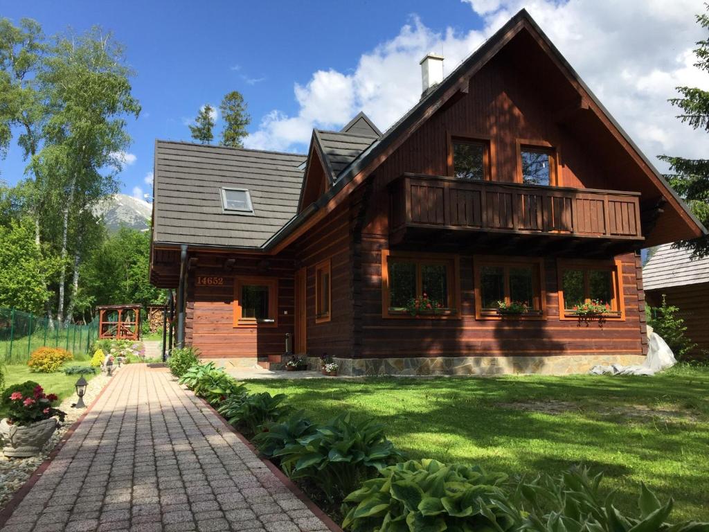 a wooden house with a brick walkway in front of it at Villa Milan in Vysoke Tatry - Tatranska Lomnica.