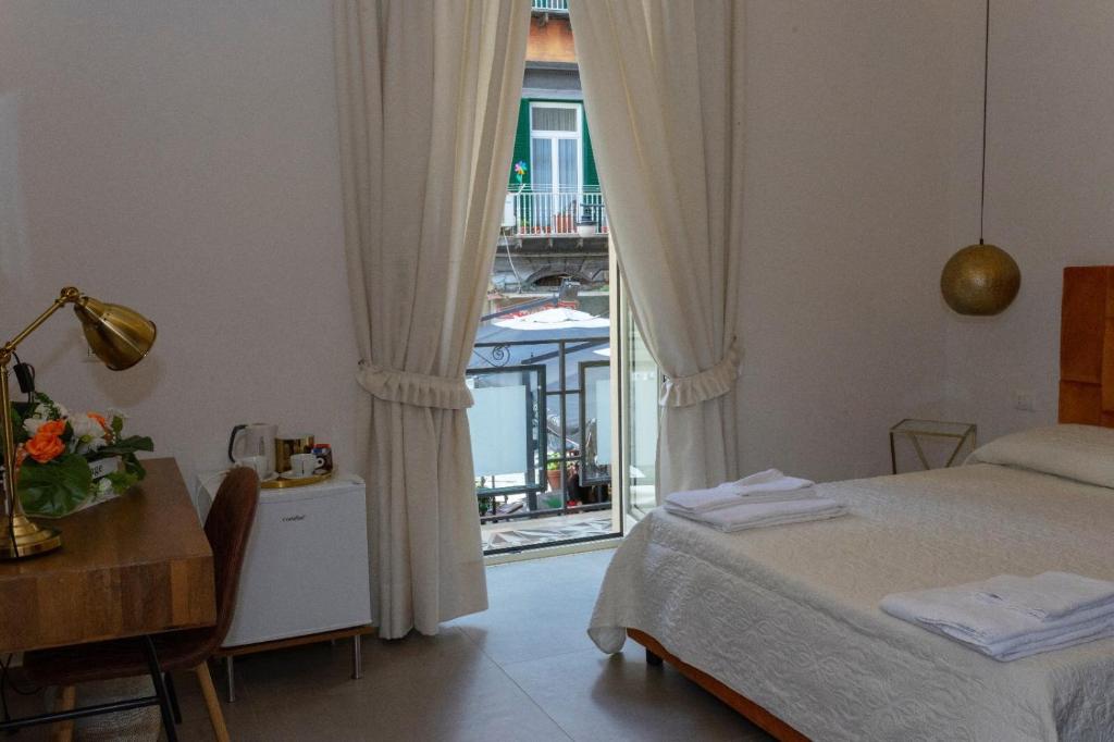 1 dormitorio con cama, mesa y ventana en “A piazzetta”, en Nápoles