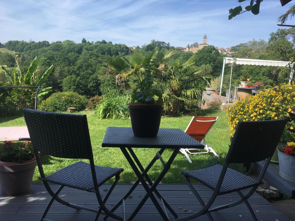 2 sillas y una mesa con una maceta en el patio en Les Conches, Chambres d'Hôtes et Gite, en Thiviers