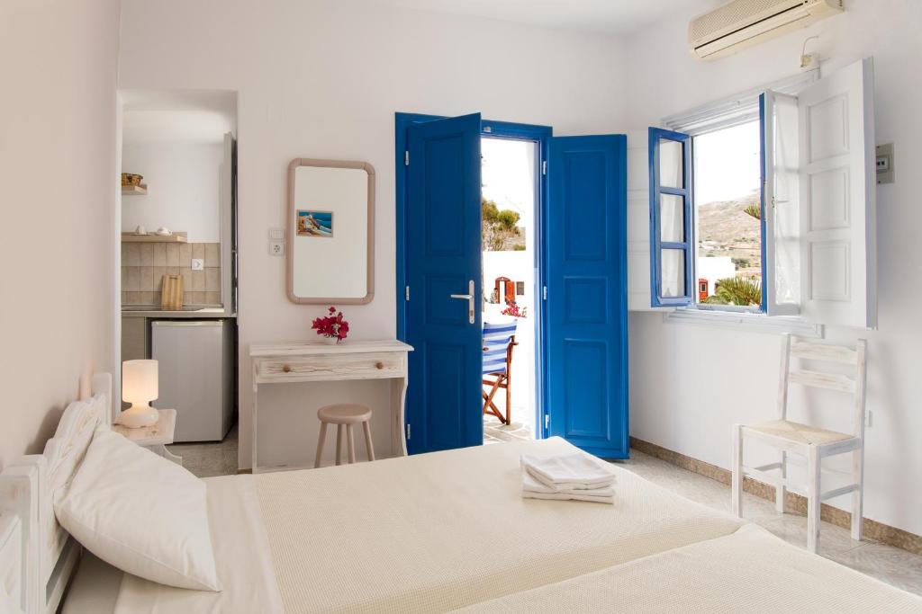 salon z niebieskimi drzwiami i stołem w obiekcie Evgenia Rooms and Apartments w mieście Chora Folegandros