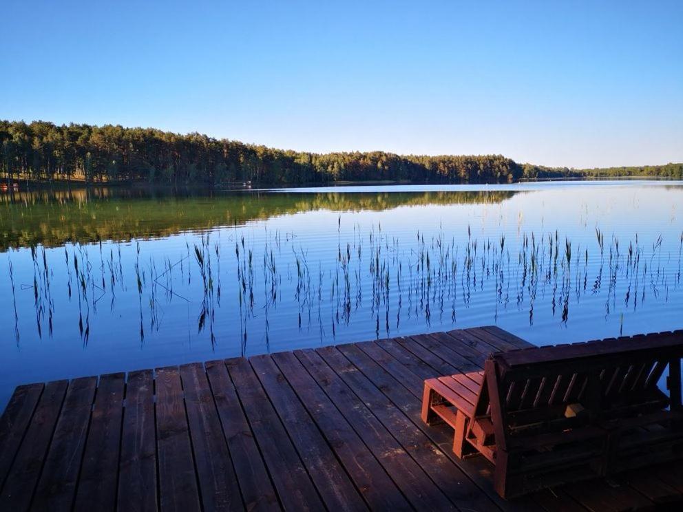 a bench sitting on a dock next to a lake at Ažuluokesos sodyba in Molėtai