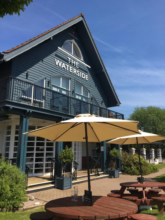 two tables and an umbrella in front of a building at Waterside by Greene King Inns in Warrington