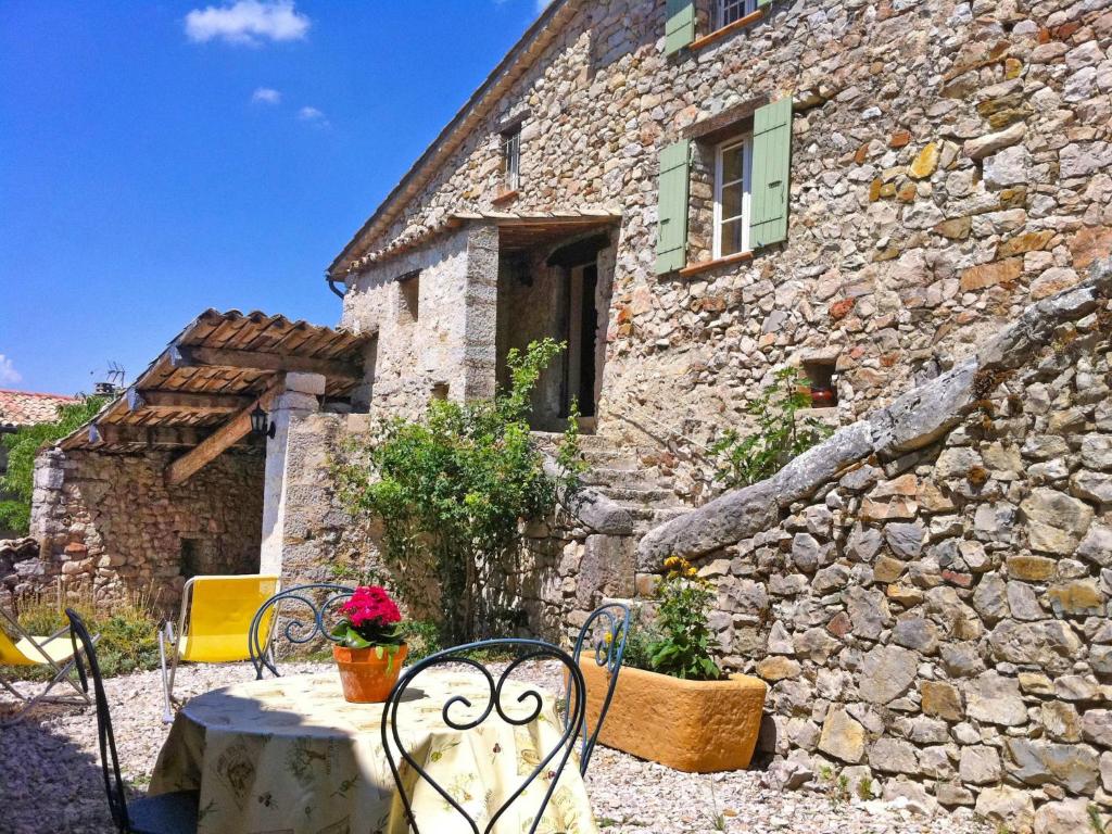 a stone house with a table and chairs in front of it at Holiday Home Du Brun by Interhome in Bésignan