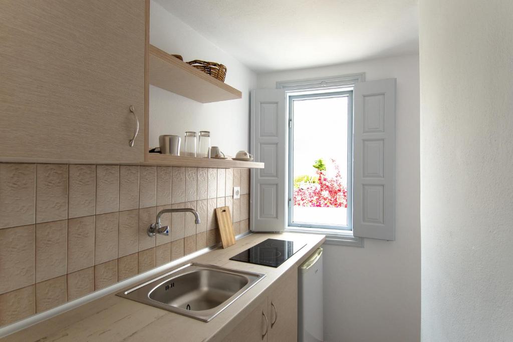 kuchnia ze zlewem i oknem w obiekcie Evgenia Rooms and Apartments w mieście Chora Folegandros
