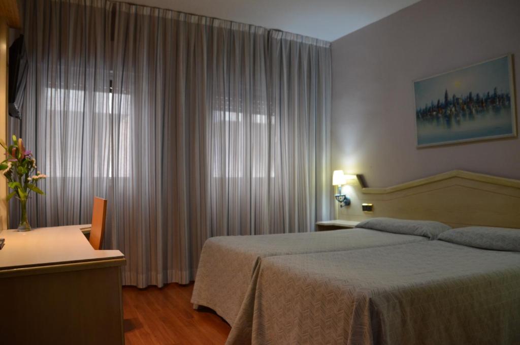 Schlafzimmer mit einem Bett und einem Fenster mit Vorhängen in der Unterkunft Ana María in Granada