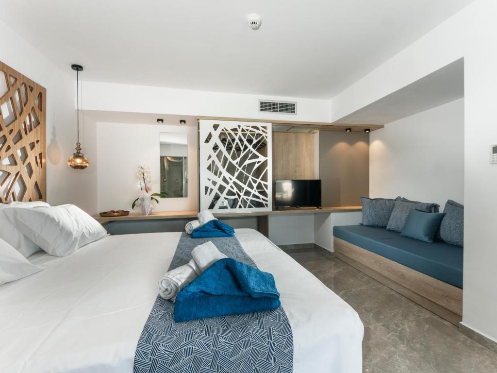 a bedroom with a large white bed and a blue couch at Lymberia Hotel in Faliraki