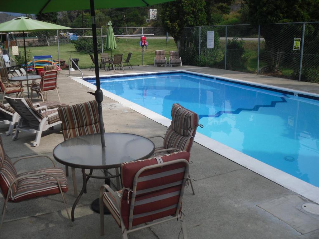 a swimming pool with chairs and a table and an umbrella at Johnny's Motel in Grand Forks