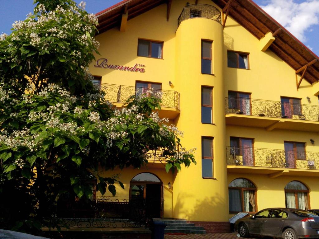 ein gelbes Gebäude mit einem davor geparkt in der Unterkunft Pensiunea Ruxandra in Baile Unu Mai
