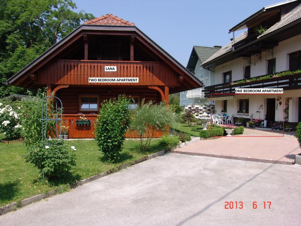 a building with a gambrel roof in a yard at Apartments Lana in Bled