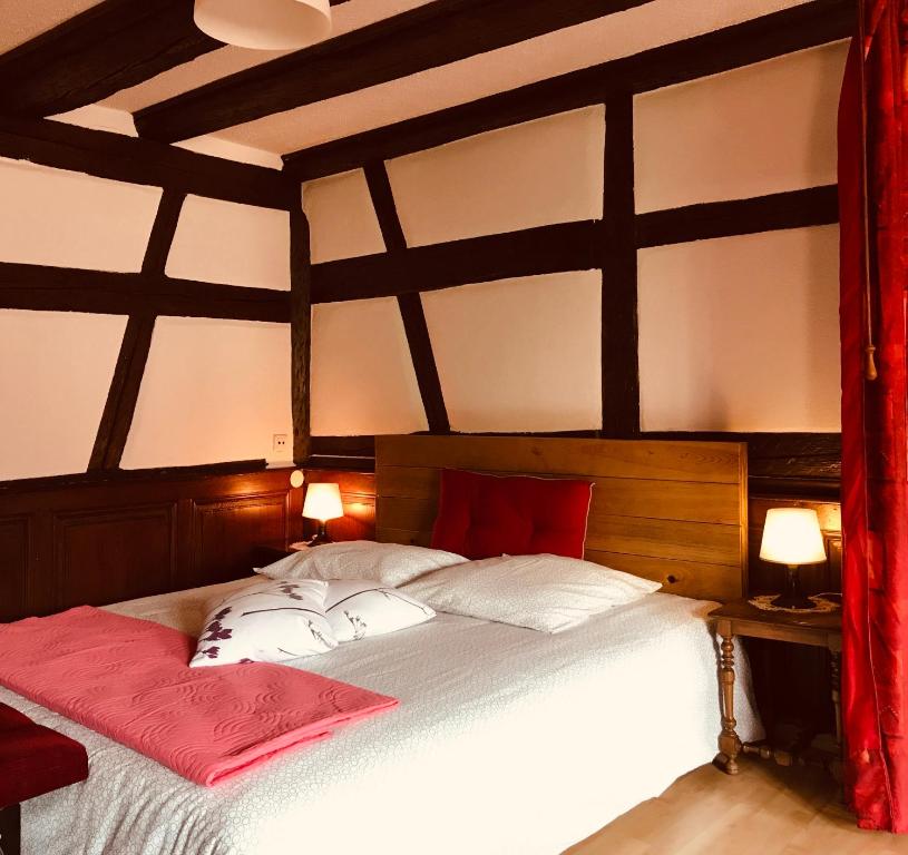 ein Schlafzimmer mit einem großen weißen Bett mit roten Kissen in der Unterkunft AUX DEUX CIGOGNES AMMERSCHWIHR in Ammerschwihr