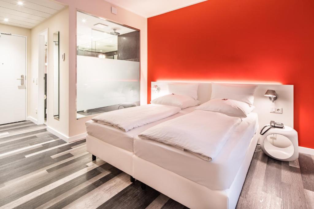 ein Schlafzimmer mit einem weißen Bett und einer roten Wand in der Unterkunft Cityhotel am Thielenplatz in Hannover