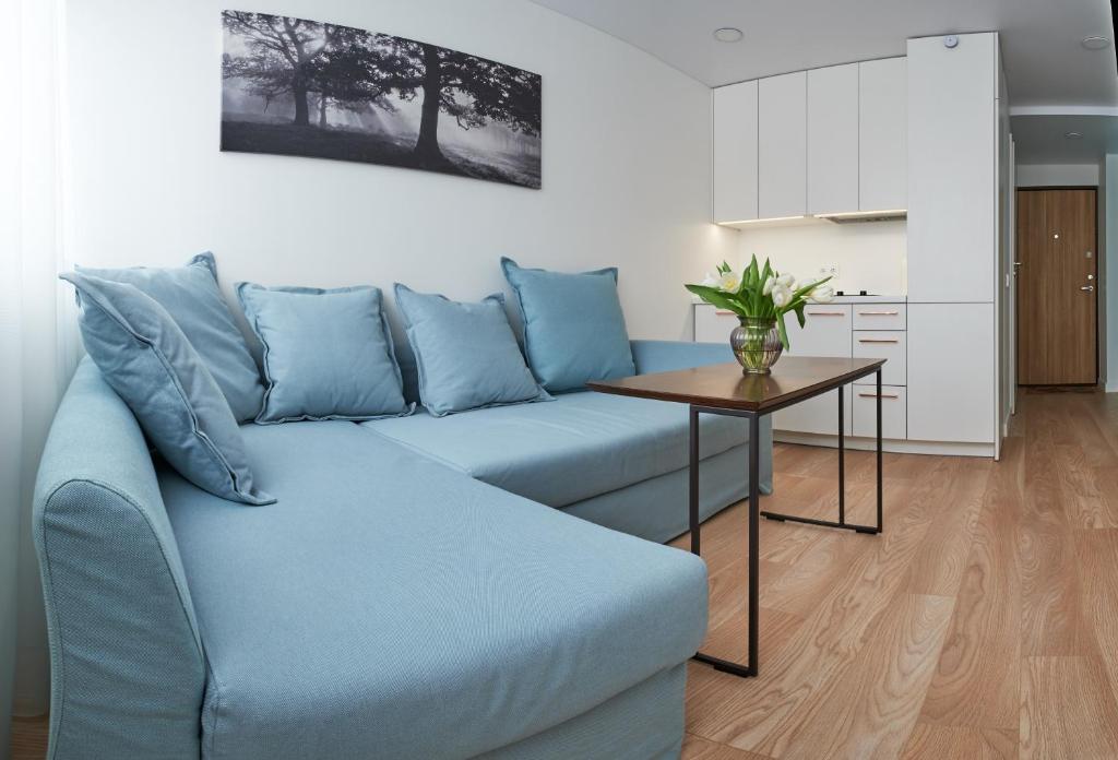 ein blaues Sofa im Wohnzimmer mit einem Tisch in der Unterkunft Cosy studio near Akropolis and Švyturio arena in Klaipėda