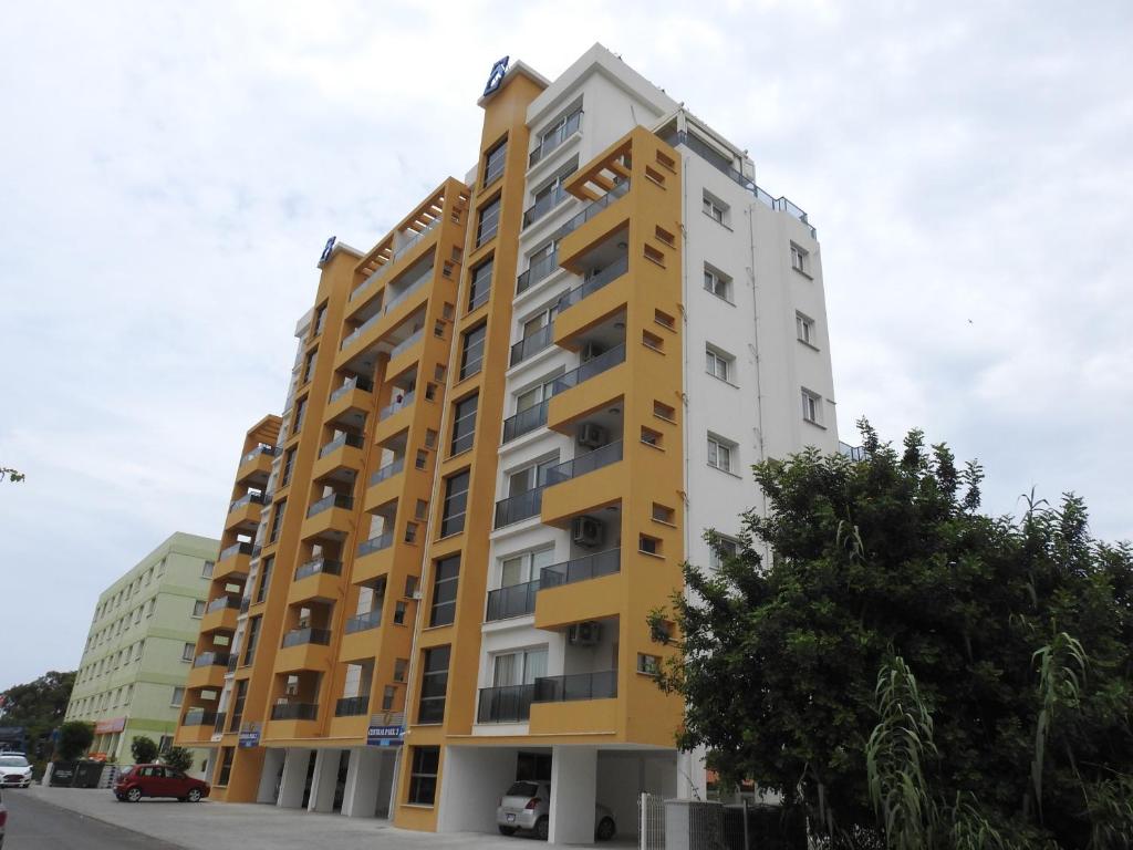 a tall yellow and white apartment building at Alp Apartment in Famagusta