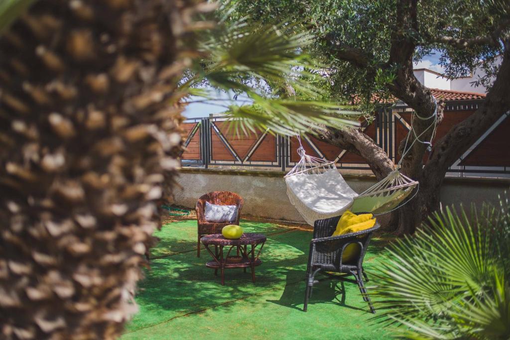eine Hängematte im Garten mit Stühlen und einem Tisch in der Unterkunft Alessandro House in Porto Cesareo