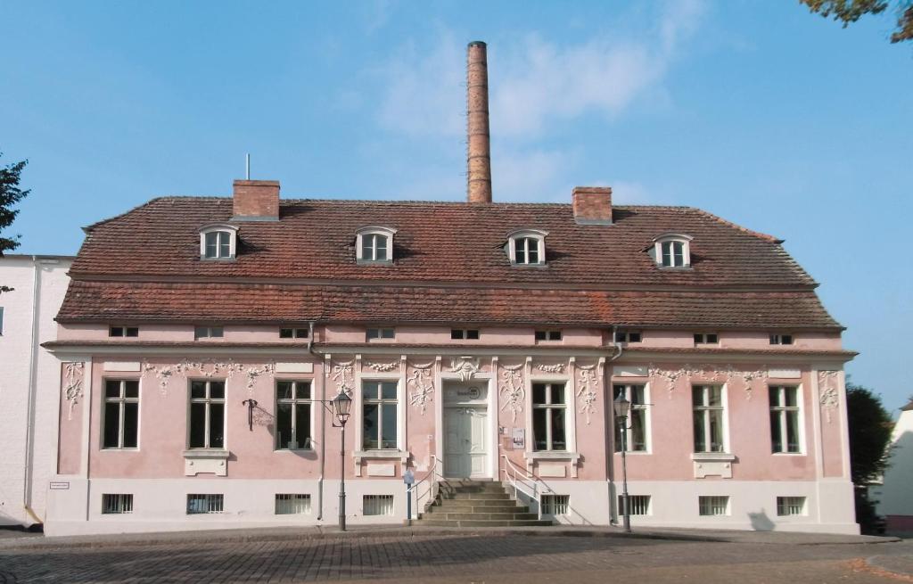 ein altes rosafarbenes Haus mit Kamin in der Unterkunft Lendelhaus & Historische Saftfabrik Werder in Werder